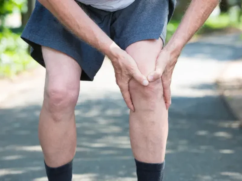 A person holding their knee in pain outdoors