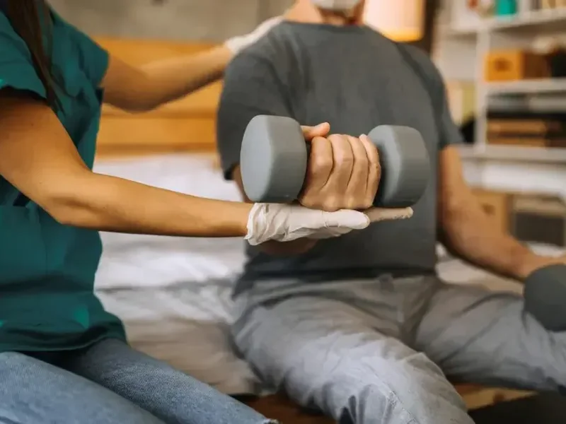 A physical therapist assisting a patient with a hand-weight exercise